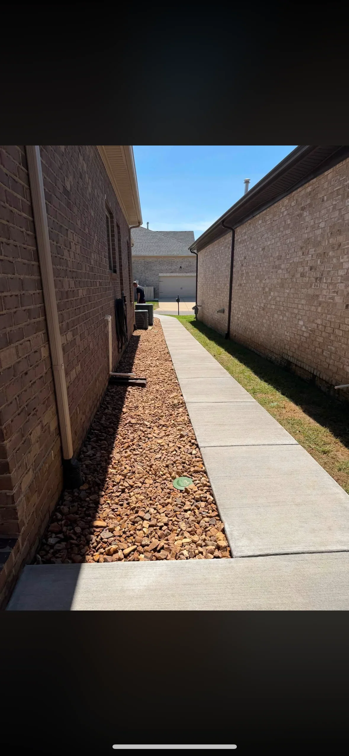 Concrete walkway with river rock mulch beds between brick home walls